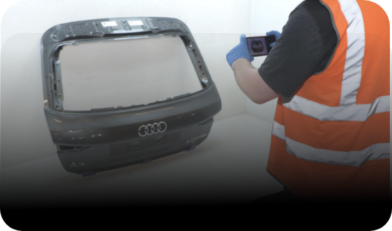 Person in high-visibility vest taking a photo of the rear panel from an Audi car 