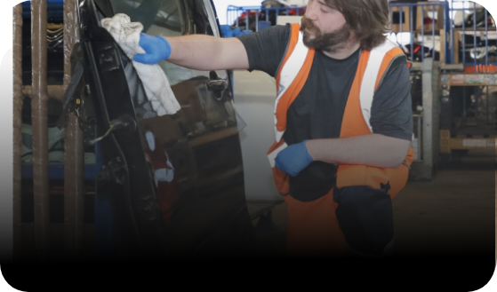Person cleaning a reclaimed car door ready for distribution